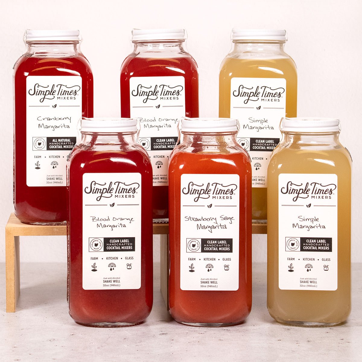 Front view of Margarita Variety 6-Pack showcasing six mixer bottles in red, pink, and golden hues on a white background