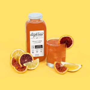 Front view of Blood Orange Lemonade cocktail mixer showcasing its bottle with a citrus-garnished drink on a yellow background